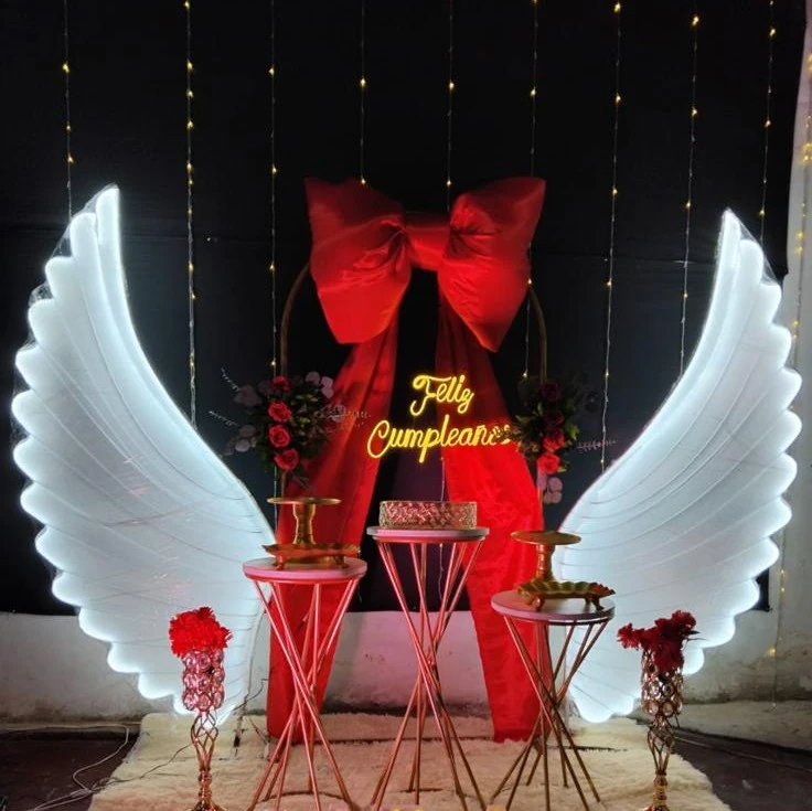 Alas blancas iluminadas con lazo rojo y mesas doradas