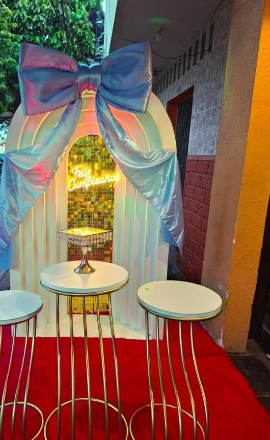 Arco blanco con lazo iridiscente y mesas altas