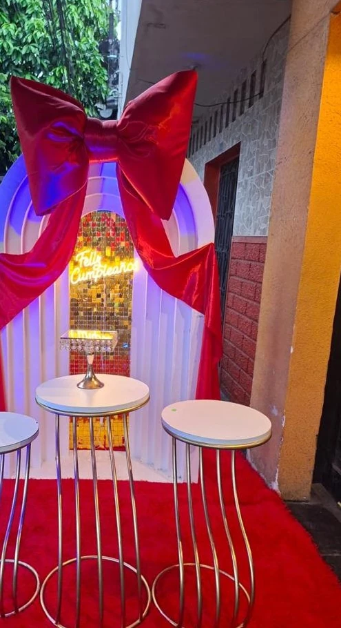 Arco blanco con lazo rojo y mesas altas