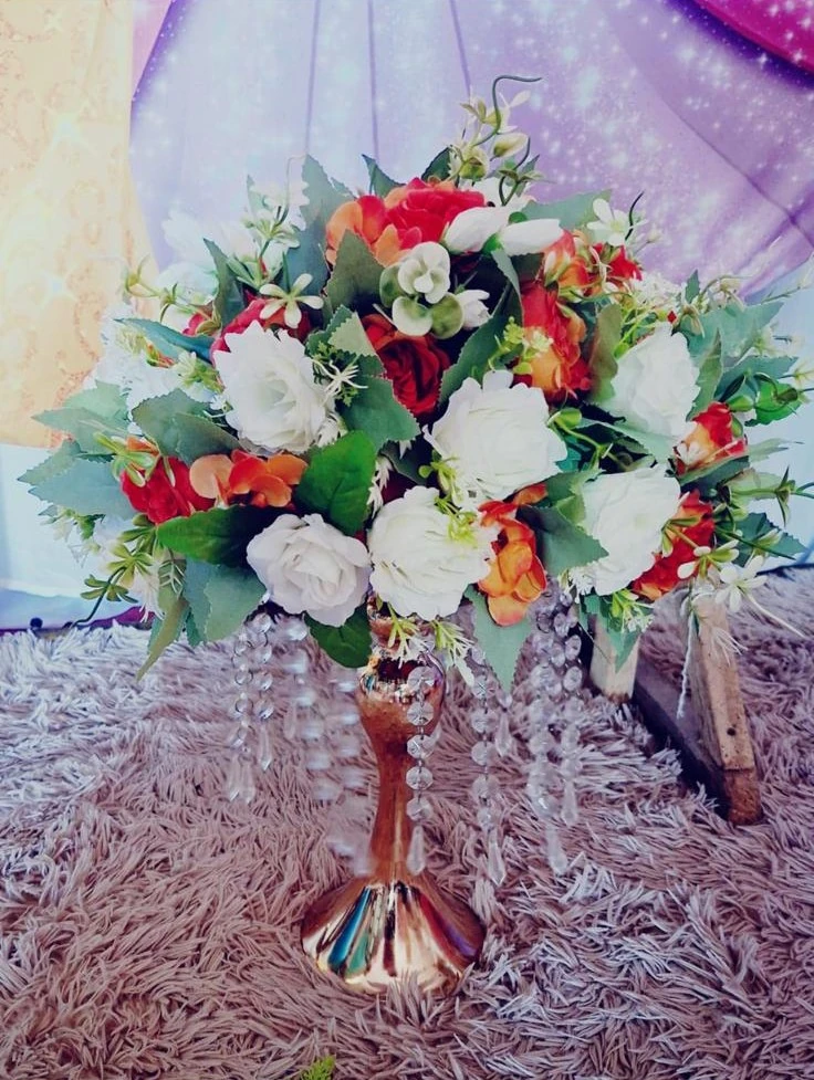 Centro de mesa alto con flores blancas, rojas y follaje verde