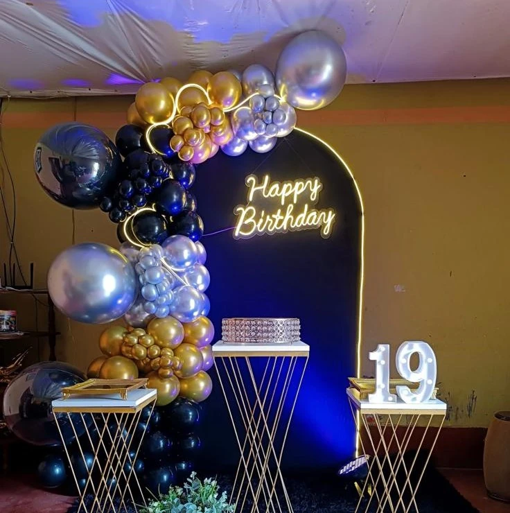 Montaje azul, negro y dorado con globos, mesas altas y luces