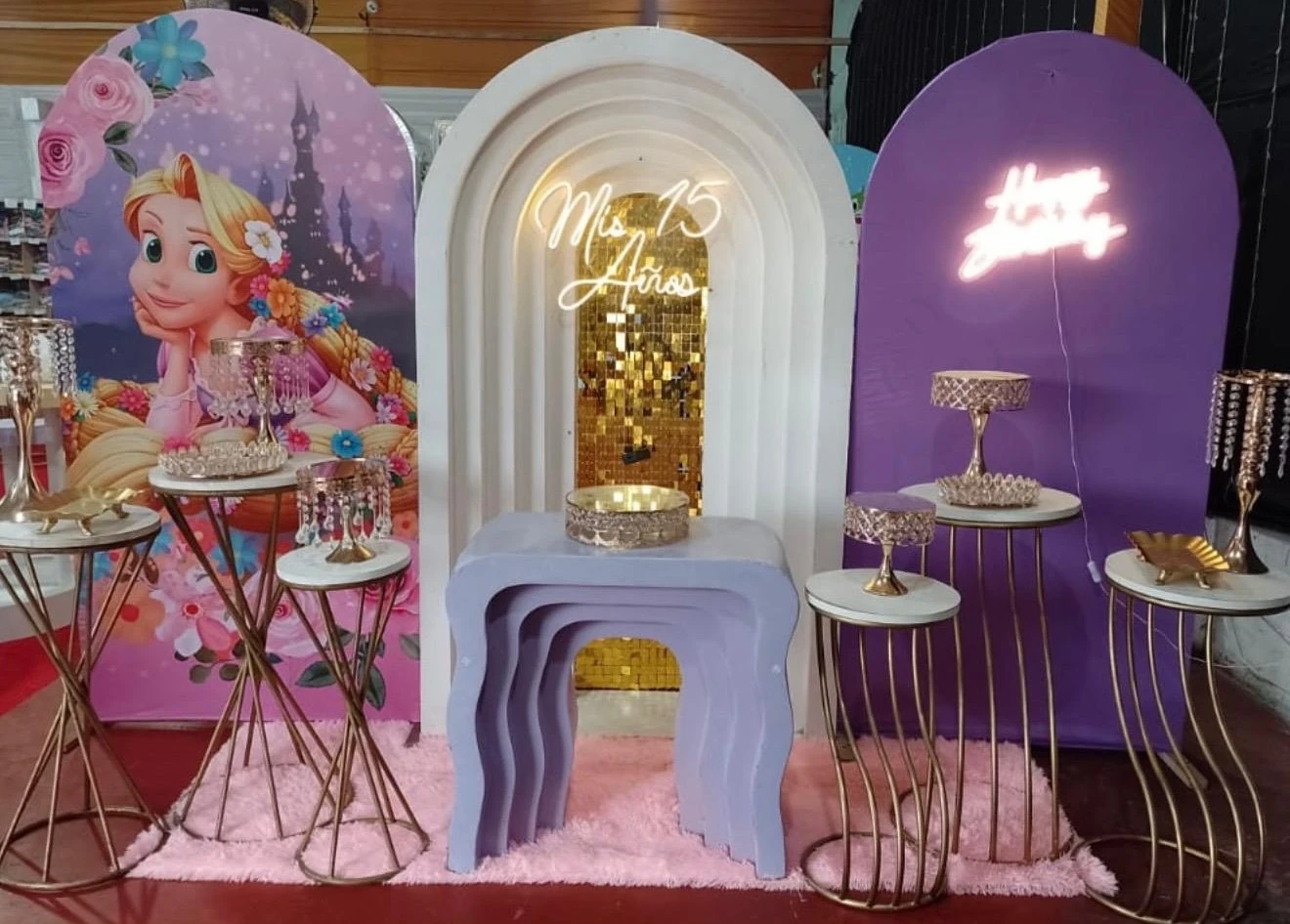 Escenario lila y dorado de quince años con arcos y mesas altas