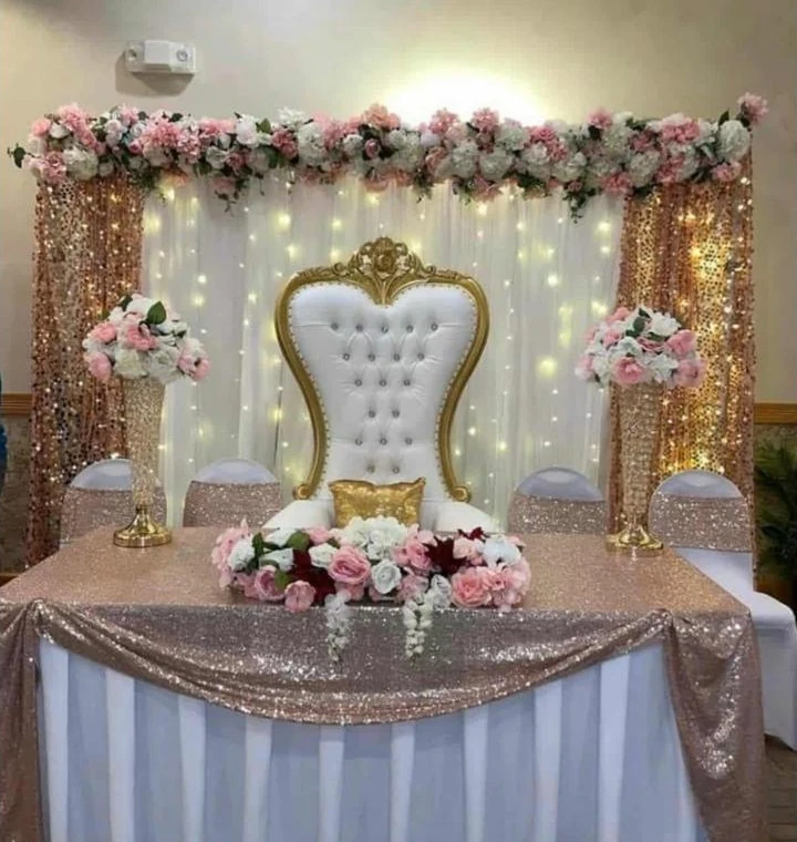 Mesa principal con sillón virreinal, cortinas doradas y flores rosadas