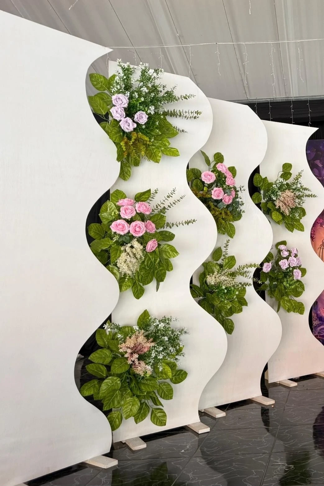 Paneles blancos ondulados con follaje y flores rosadas