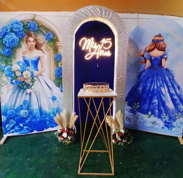 Escenario azul de quince años con paneles ilustrados, arco iluminado y mesa alta
