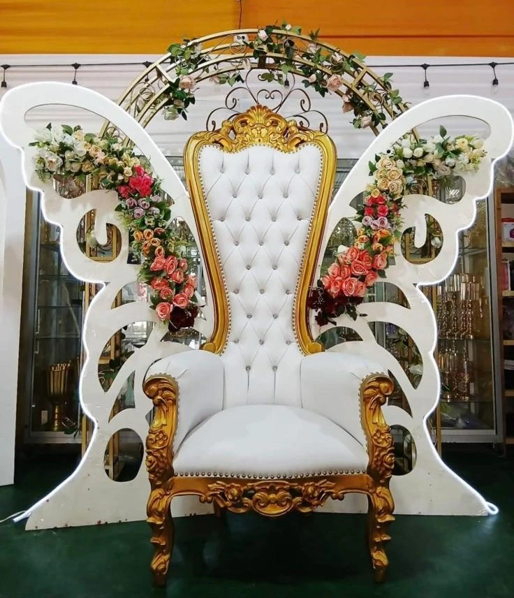 Sillón blanco y dorado frente a un panel de mariposa