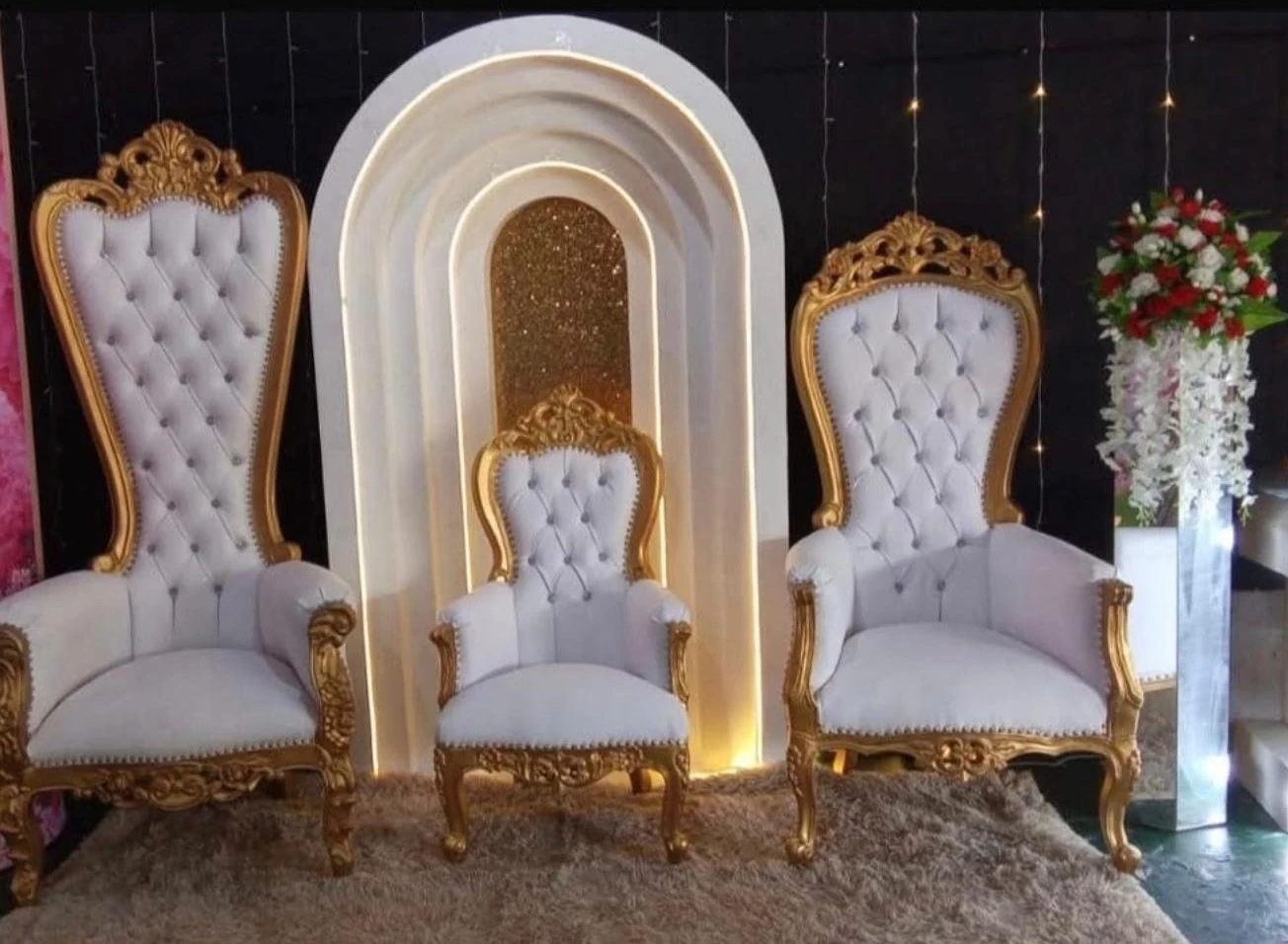 Sillones blancos y dorados frente a arcos iluminados
