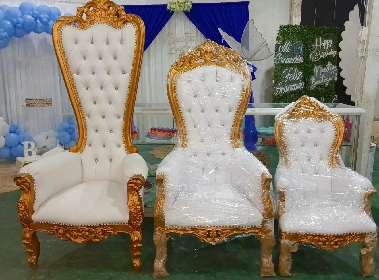 Tres sillones blancos y dorados con globos azules